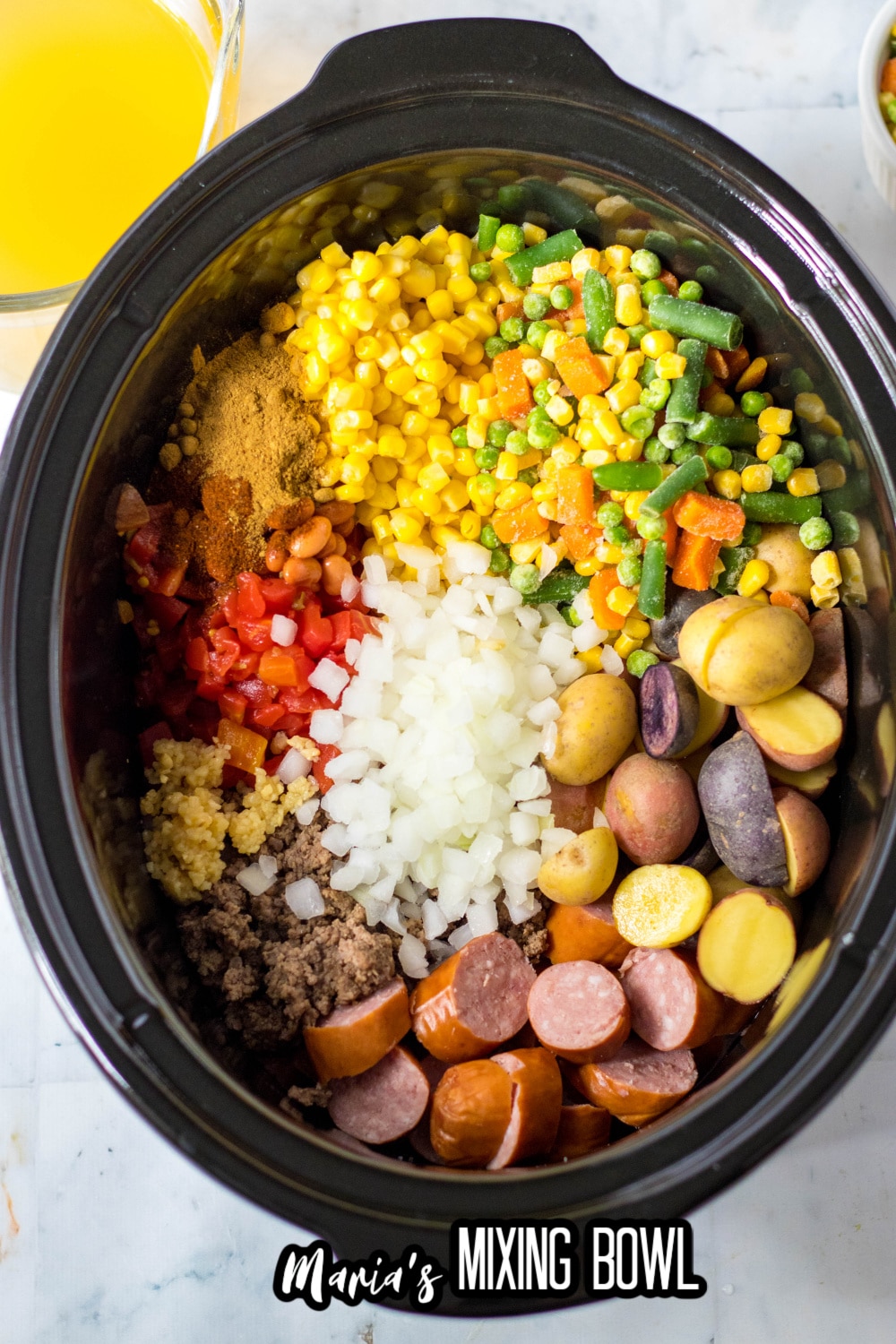 beef, kielbasa, potatoes, and vegetables in a slow cooker