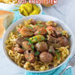 white bowl filled with egg noodles topped with slow cooker Mississippi beef stew.