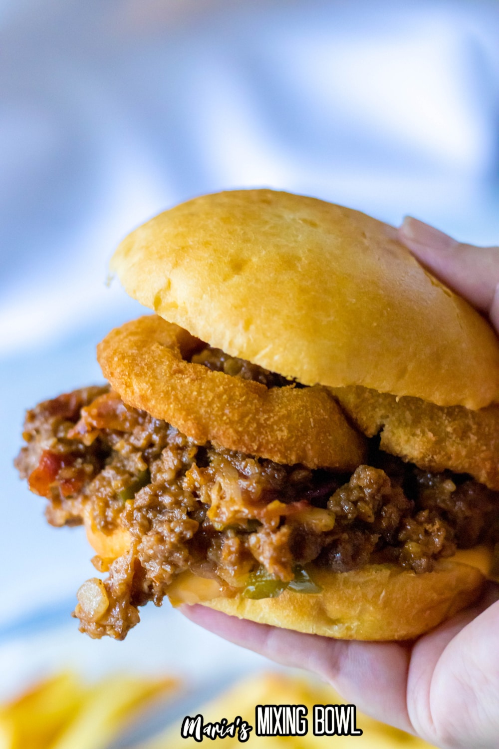 sloppy joe sandwich held in a woman's hand in the air