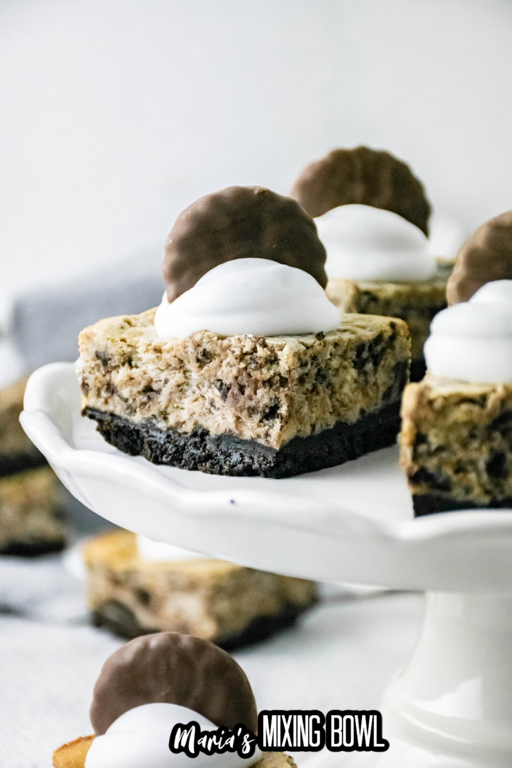 close up of thin mint cheesecake bars on a white cake stand