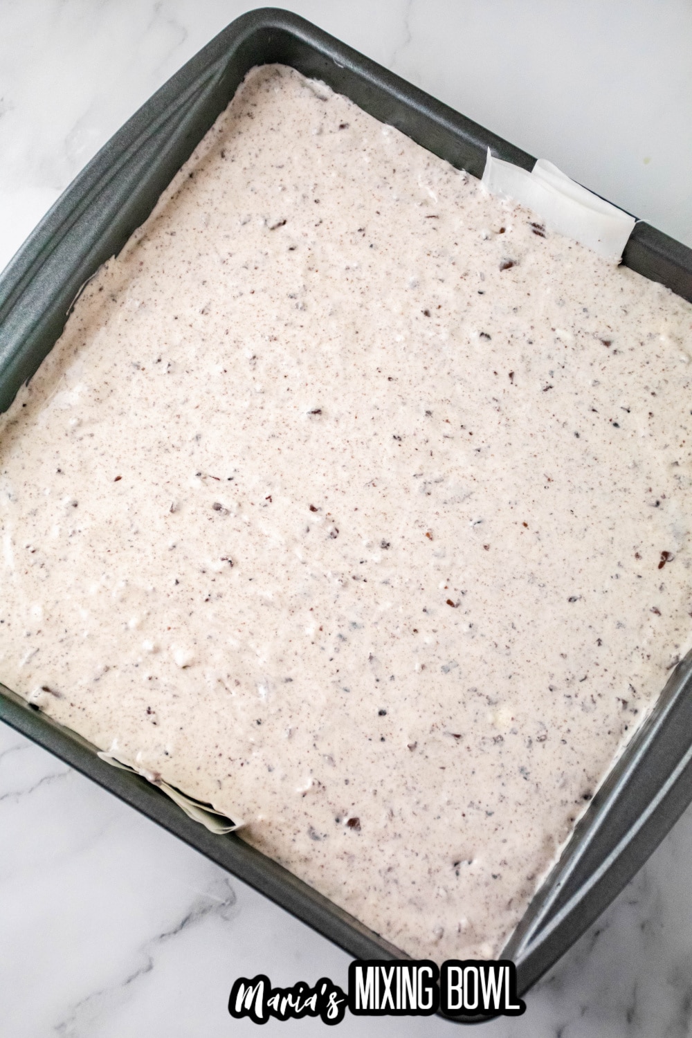 unbaked cheesecake bars in a parchment lined baking pan