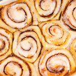 frosted cinnamon rolls in a white ceramic baking dish