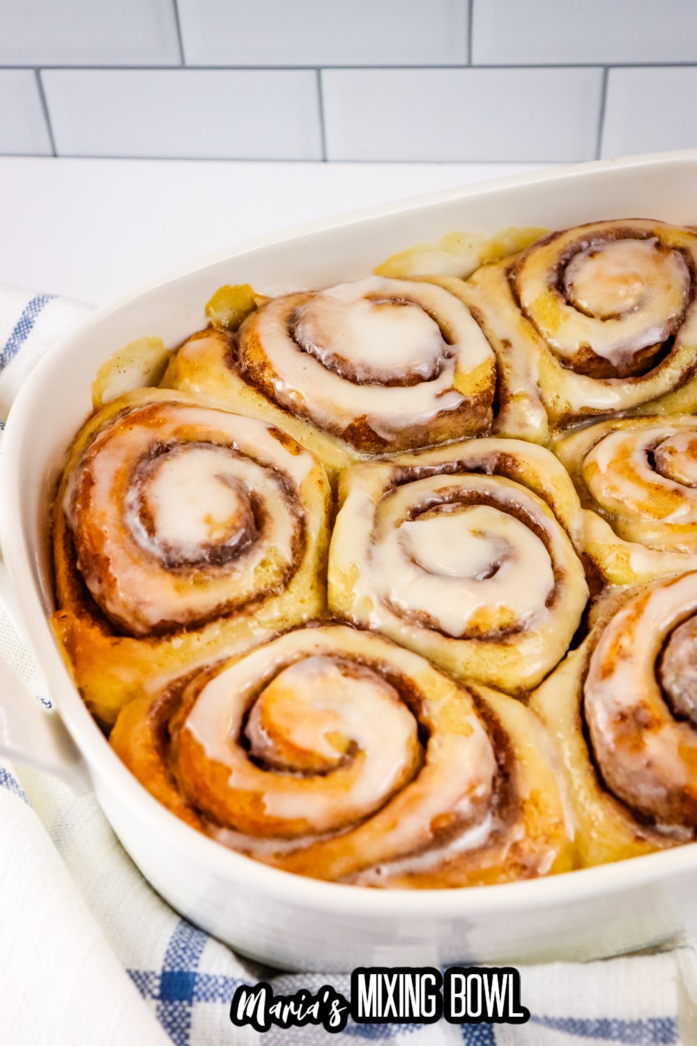 frosted cinnamon rolls in a white ceramic baking dish