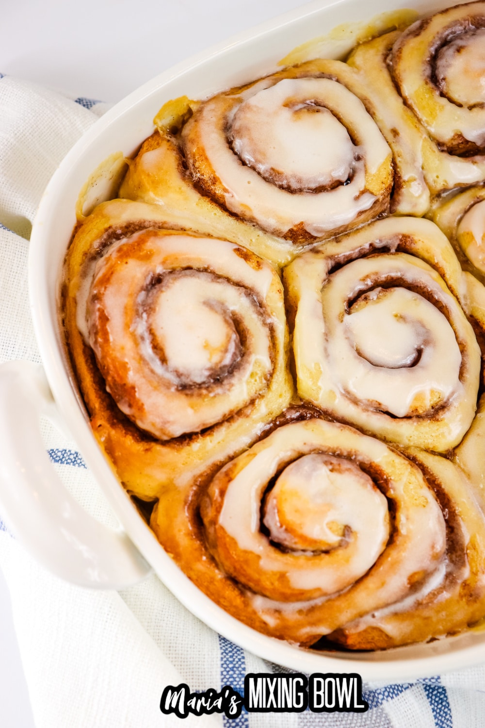 frosted cinnamon rolls in a white ceramic baking dish
