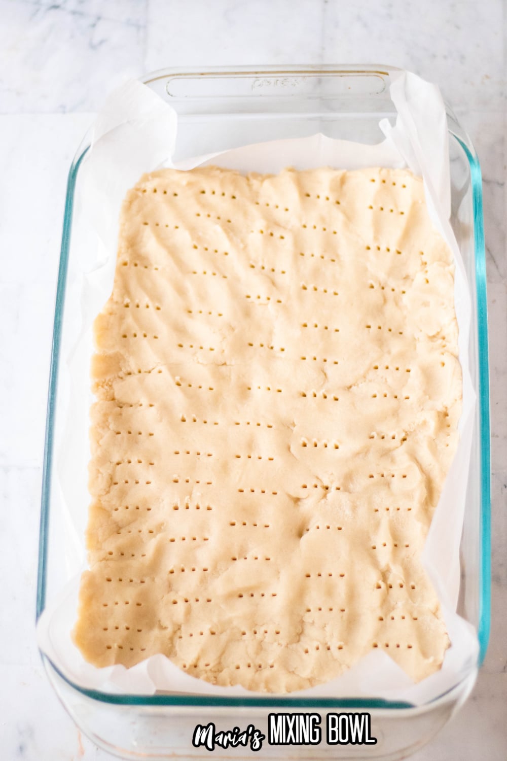 crust with holes poked into it in a parchment lined glass baking dish