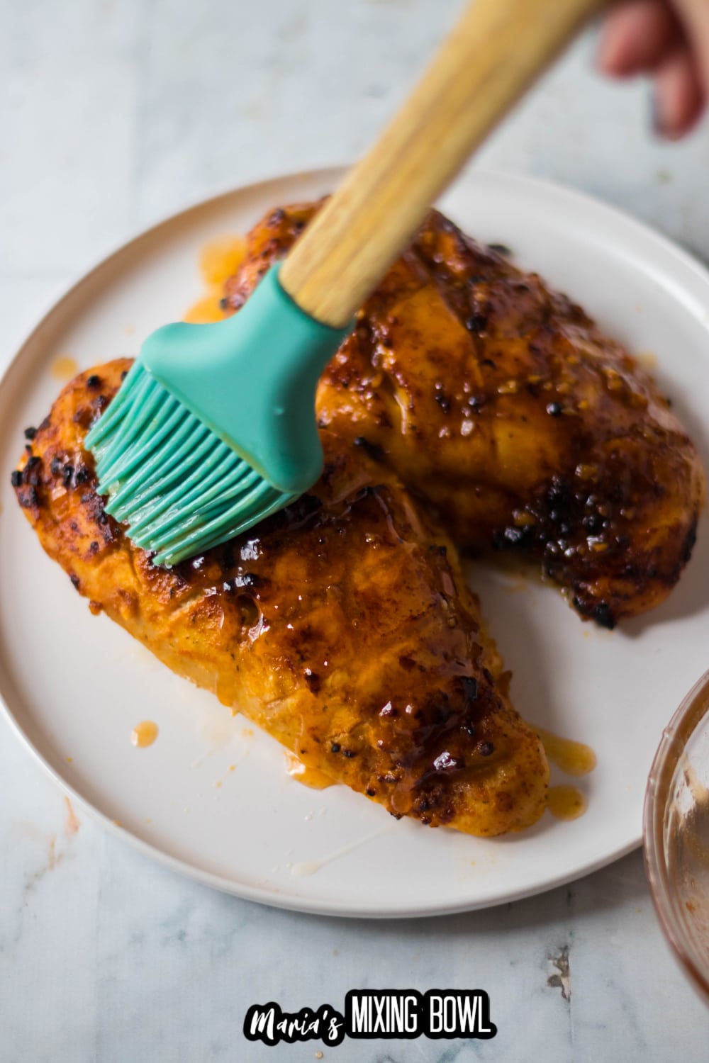 hot sauce being brushed on top of cooked chicken breast