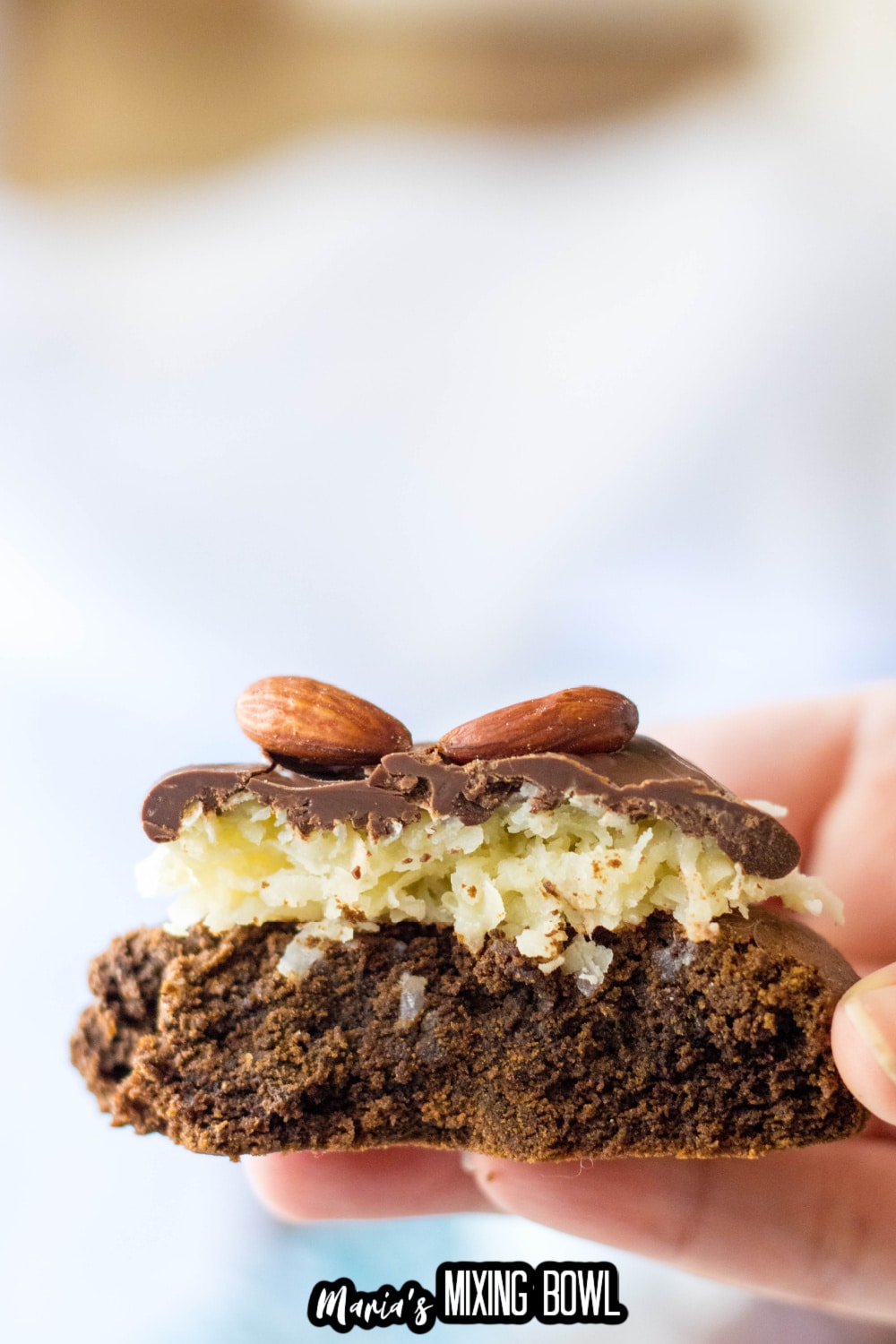 almond joy cookie held in a woman's hand after it's been bitten in half