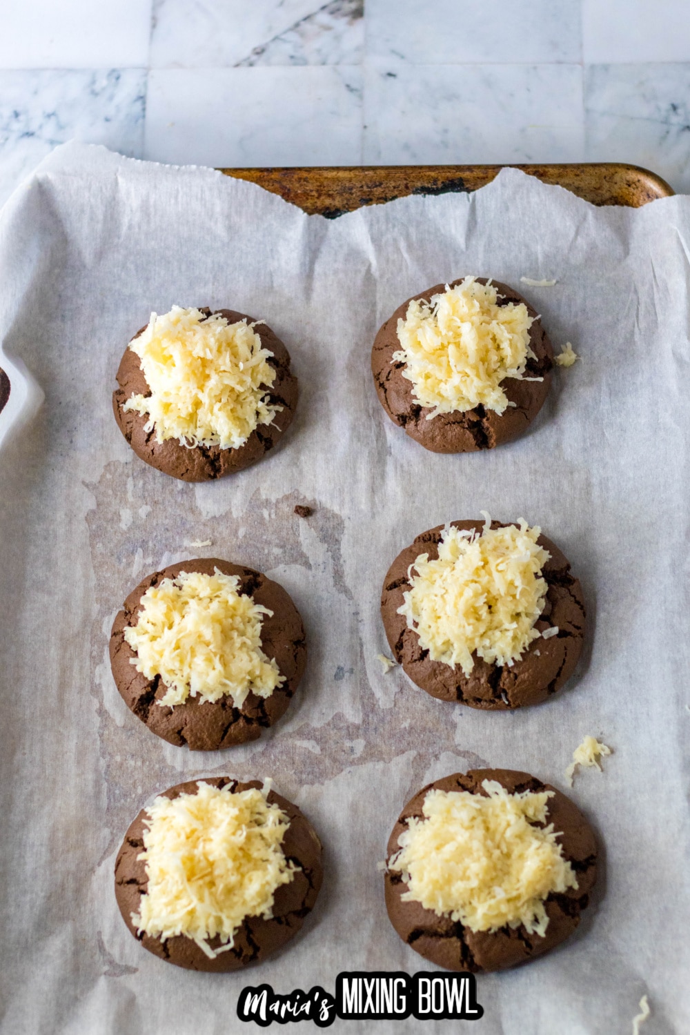 coconut being scooped on top of chocolate cookies