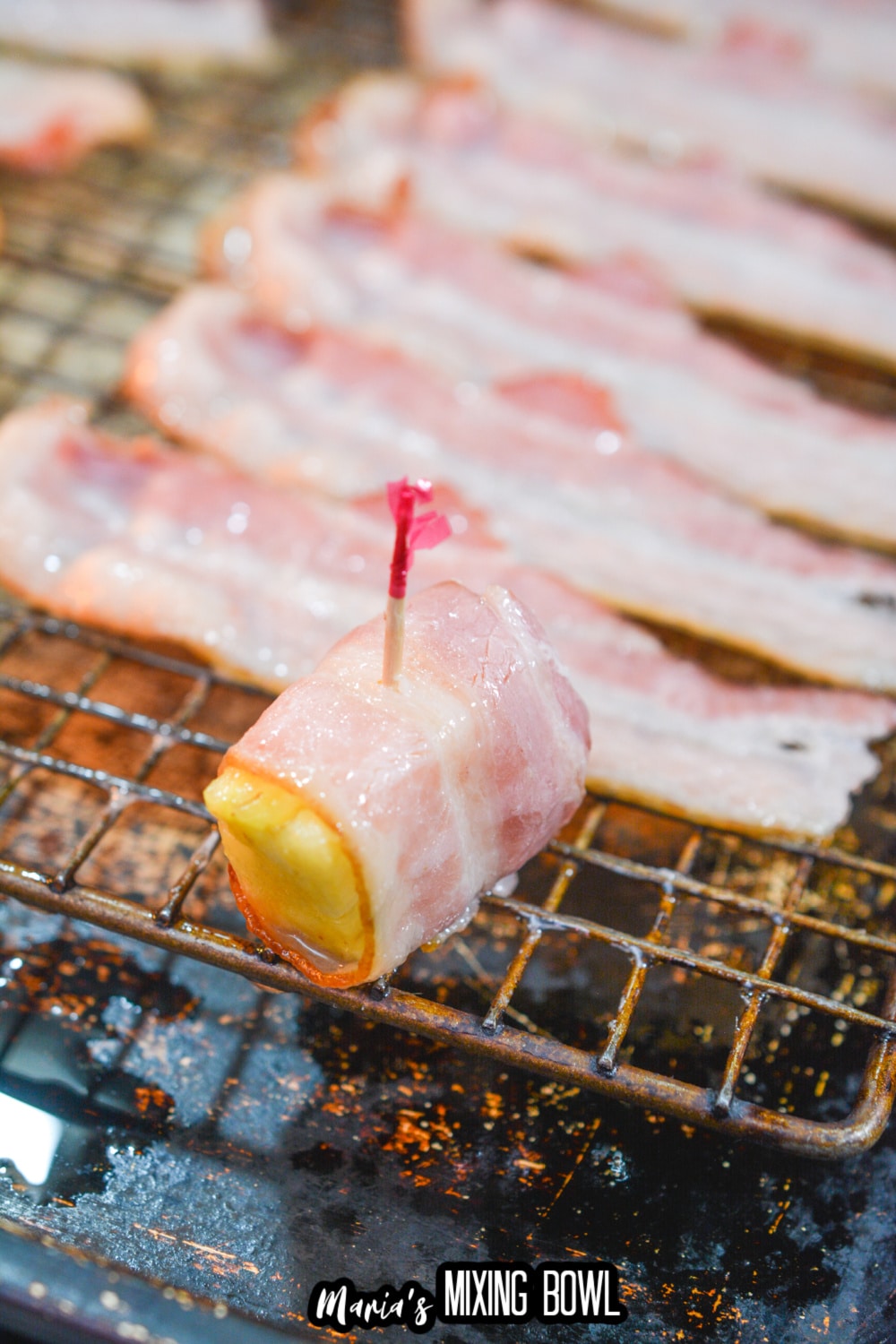 bacon wrapped pineapple on a cooling rack on a baking sheet