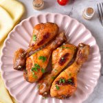 four bbq chicken legs on a light pink scalloped plate