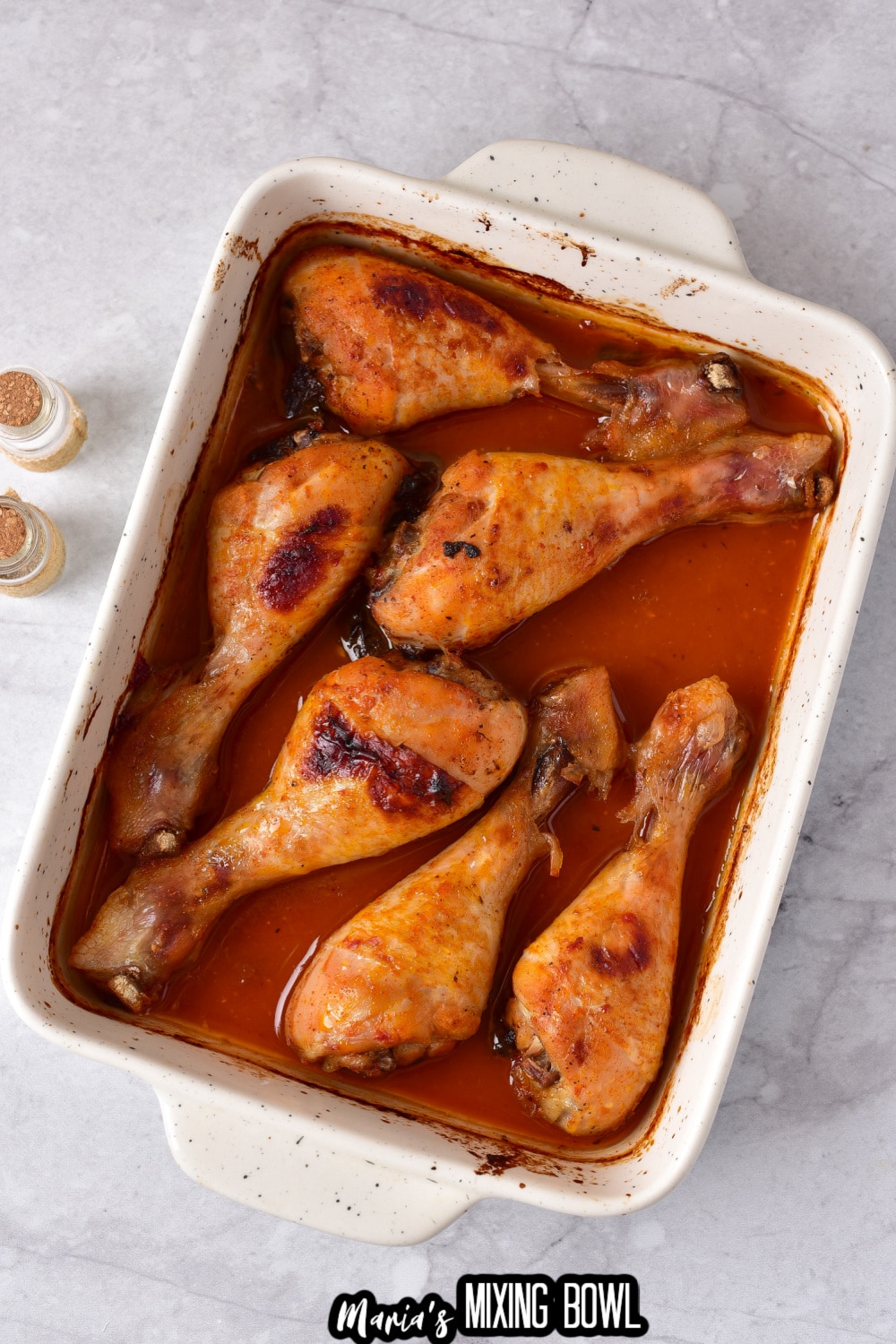 cooked chicken legs in a white baking dish