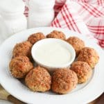 bisquick sausage balls on a white plate with a small bowl of gravy in the center