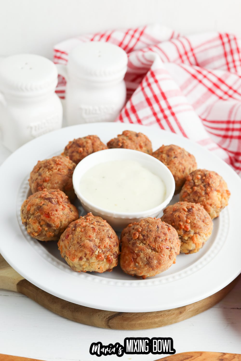 bisquick sausage balls on a white plate with a small bowl of gravy in the center