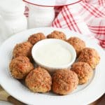 bisquick sausage balls on a white plate with a small bowl of gravy in the center