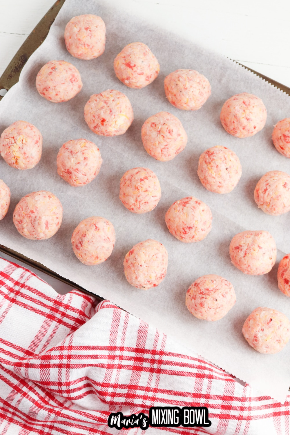 uncooked sausage balls on a parchment lined baking sheet