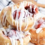 cherry muffins topped with icing, and stacked on a white plate
