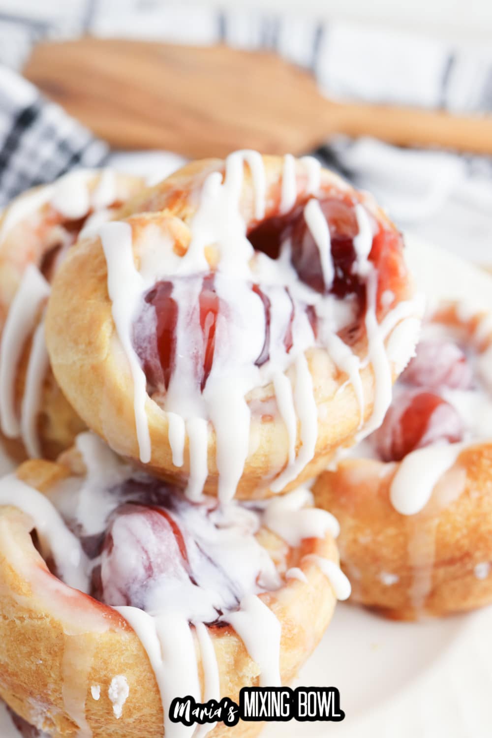 cherry muffins topped with icing, and stacked on a white plate