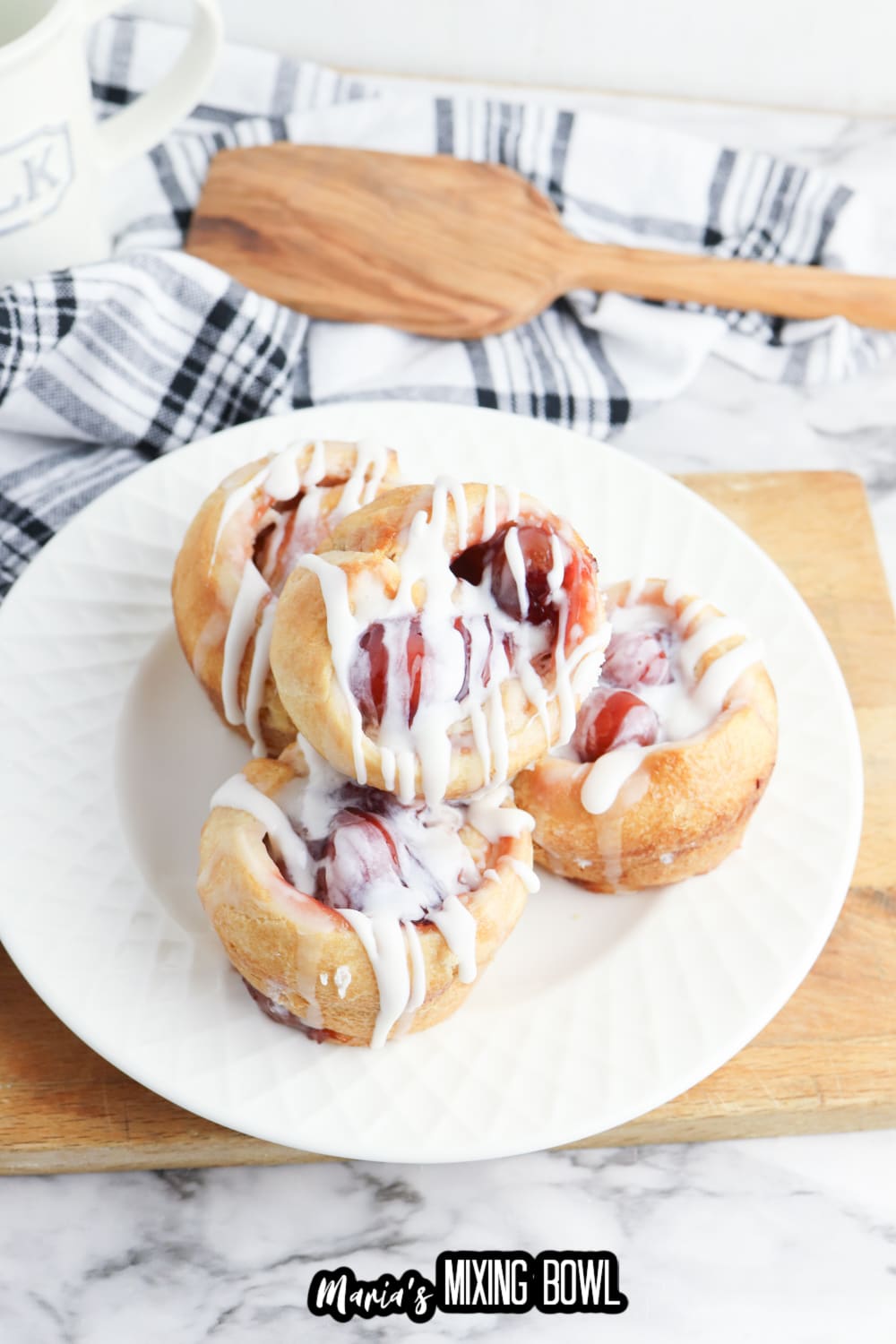 cherry muffins topped with icing, and stacked on a white plate