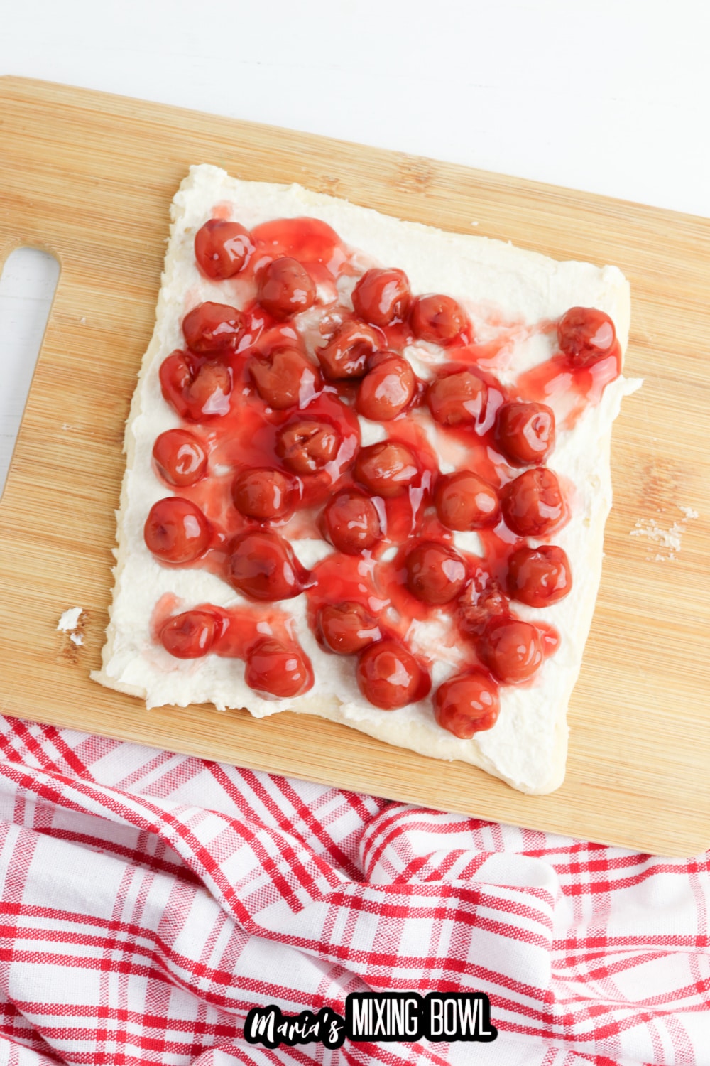 cherry pie filling being spread on crescent dough