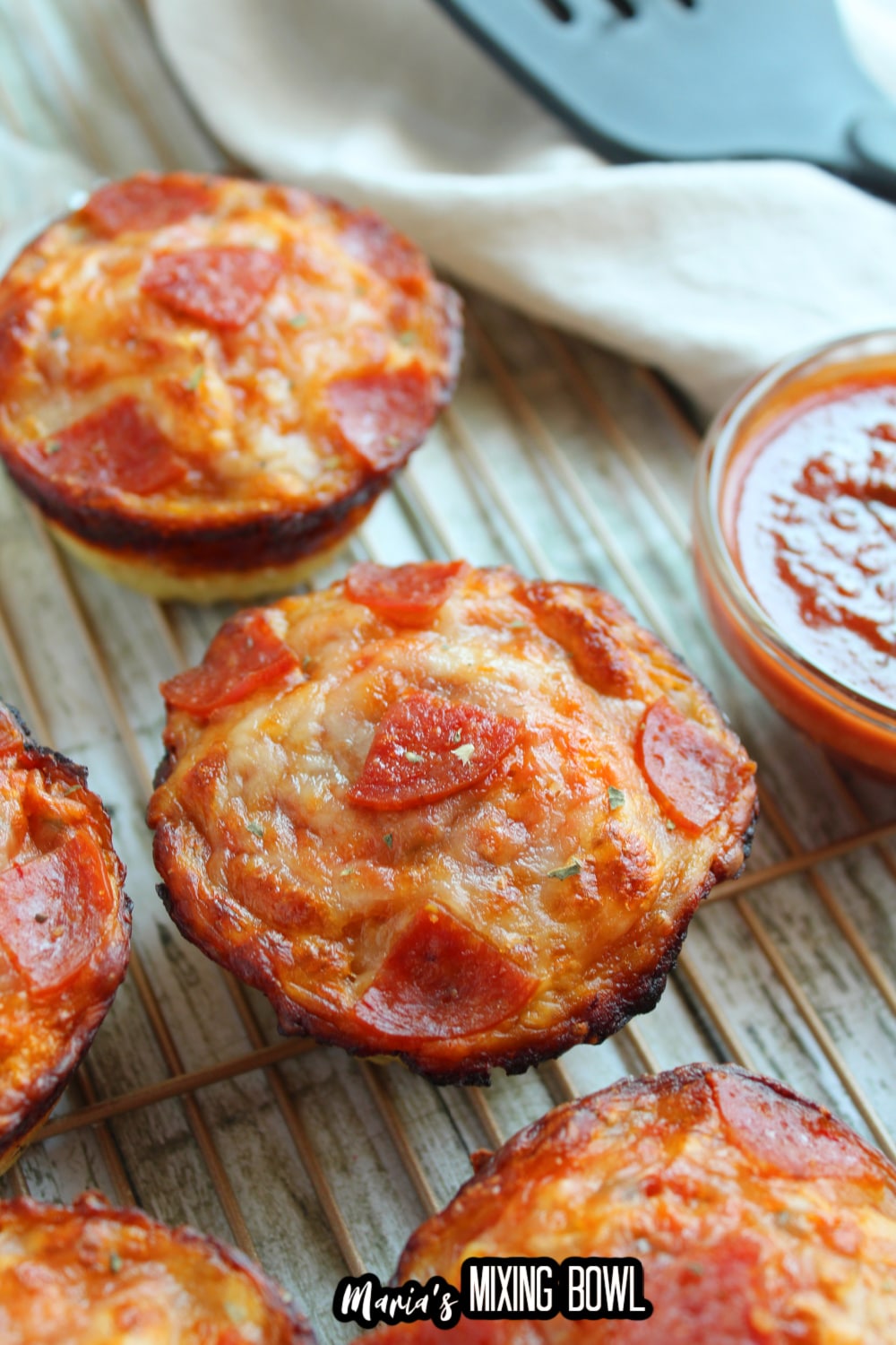 deep dish pizza bites on a wire cooling rack with a small bowl of pizza sauce on the side