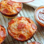 deep dish pizza bites on a wire cooling rack with a small bowl of pizza sauce on the side