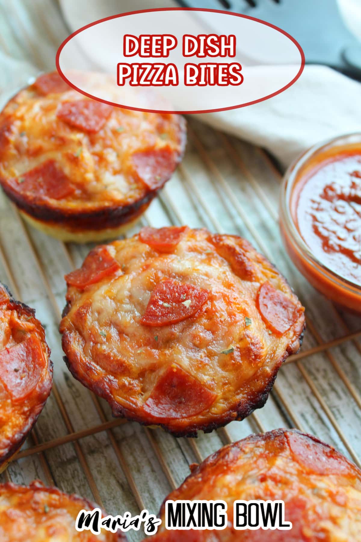 deep dish pizza bites on a wire cooling rack with a small bowl of pizza sauce on the side