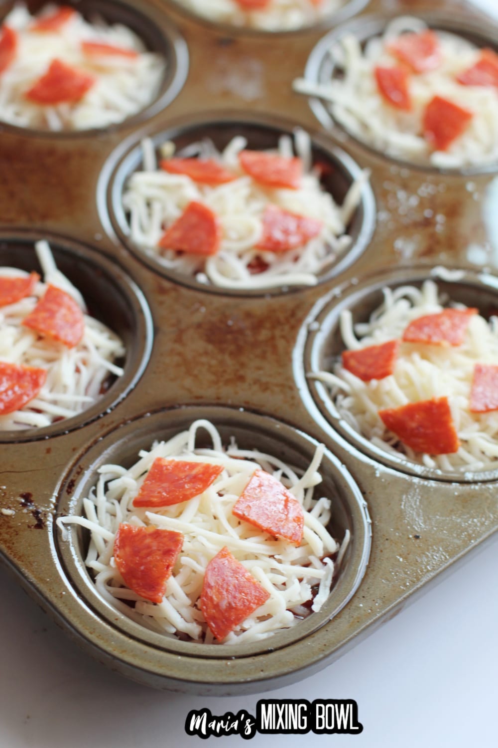 uncooked pizza bites in a muffin tin