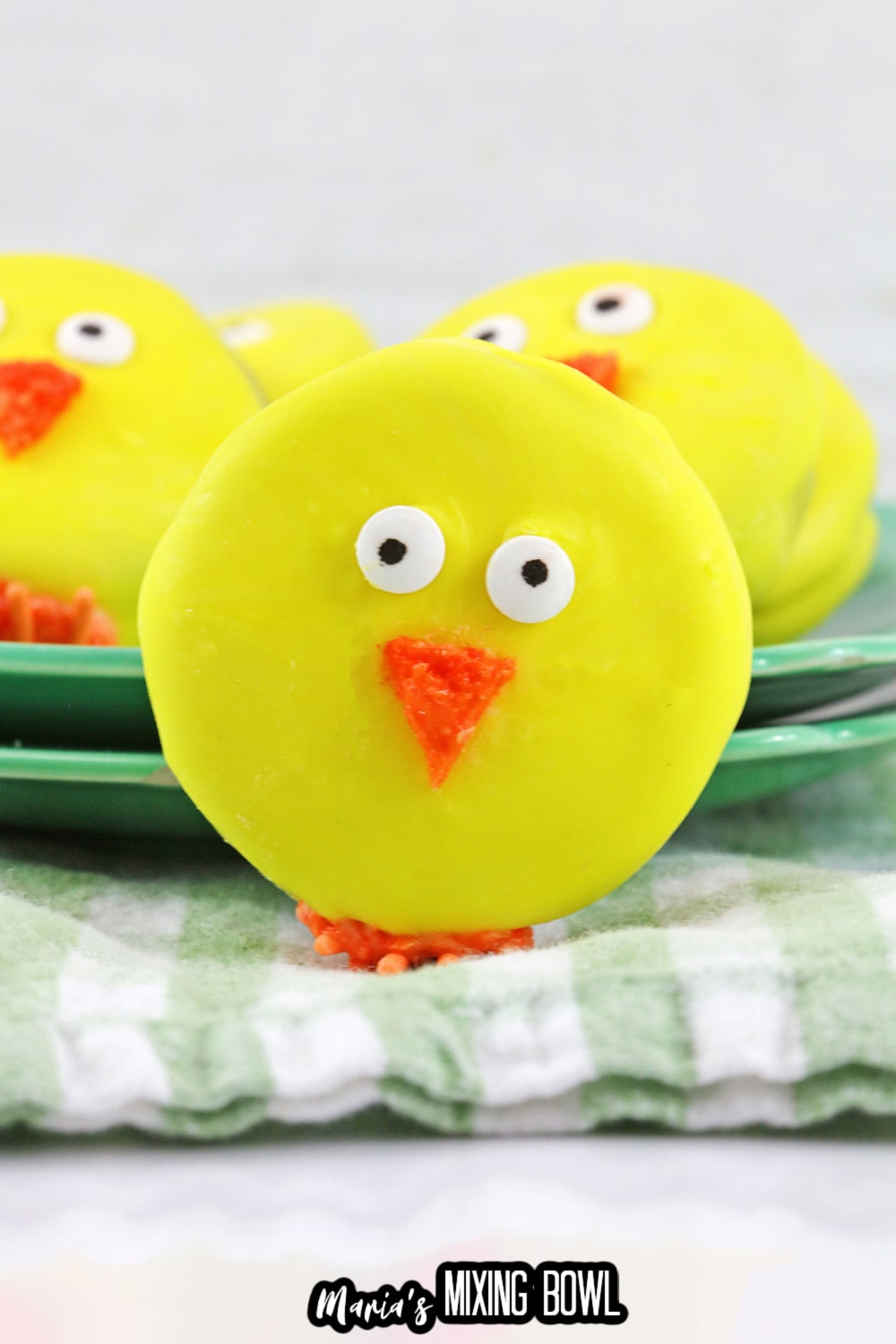 single easter chick oreo cookie with a green plate of them behind them,
