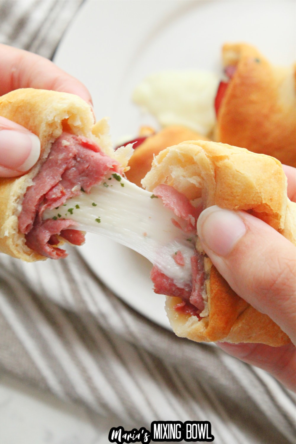 french dip crescent being spilt in half with cheese oozing in the center