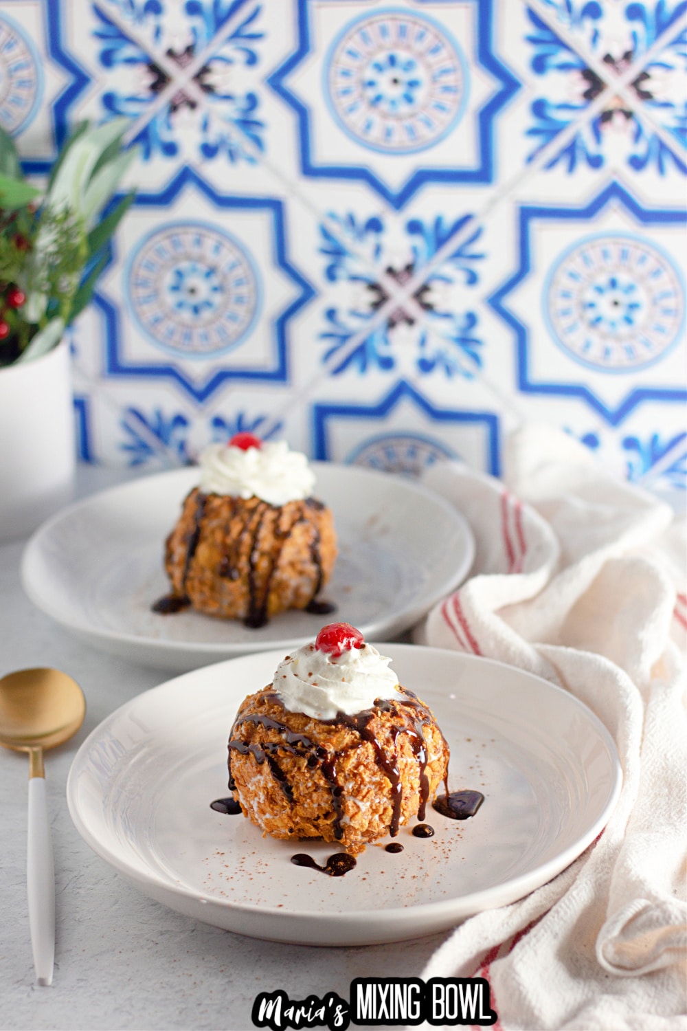 fried ice cream on a white plate topped with whipped cream and a cherry