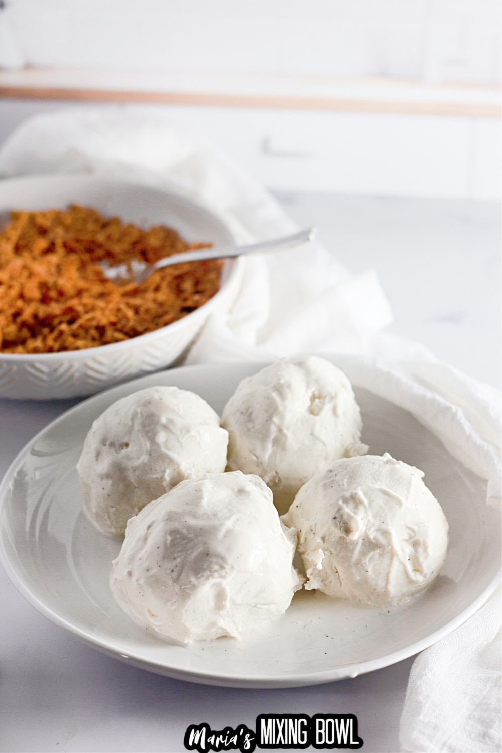 four scoops of vanilla ice cream shaped into balls on a white plate