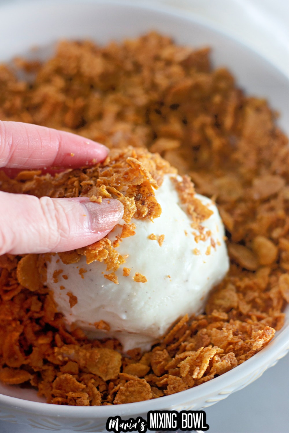 cornflakes being pressed onto an ice cream ball