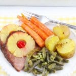 close up of ham, carrots, green beans, and potatoes on a white plate