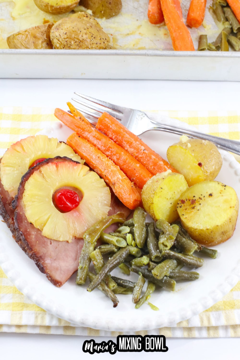 close up of ham, carrots, green beans, and potatoes on a white plate