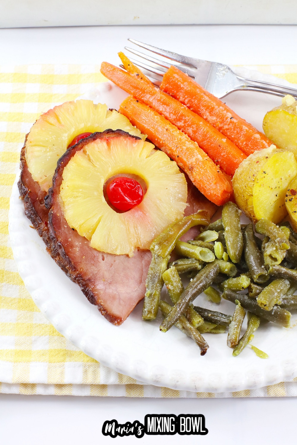 close up of ham, carrots, green beans, and potatoes on a white plate