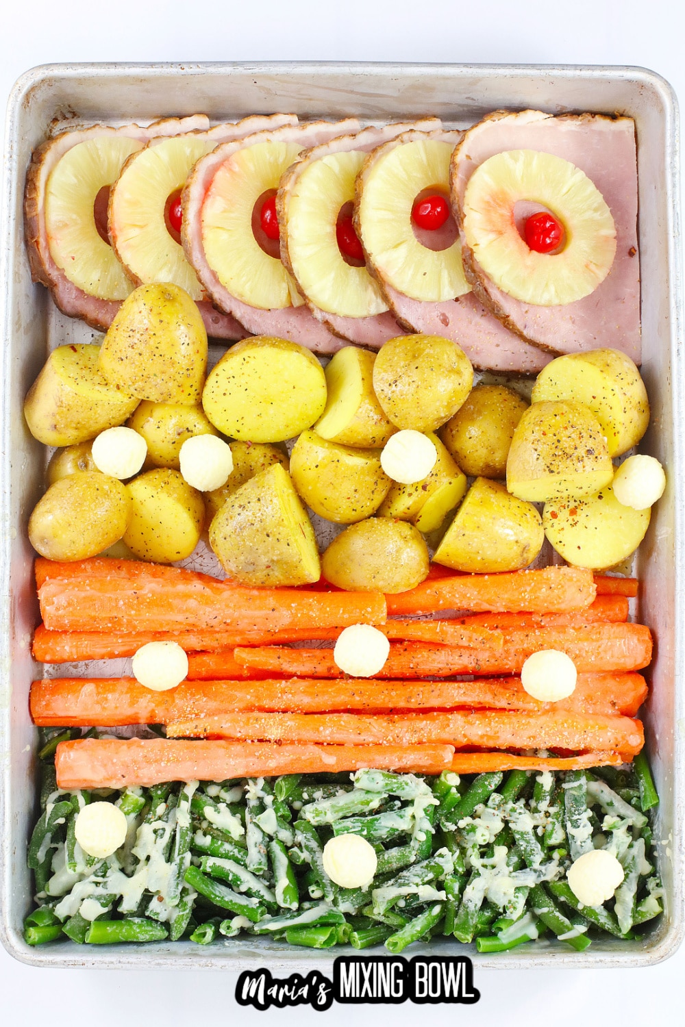 ham. potatoes, carrots, and green beans uncooked on a baking dish