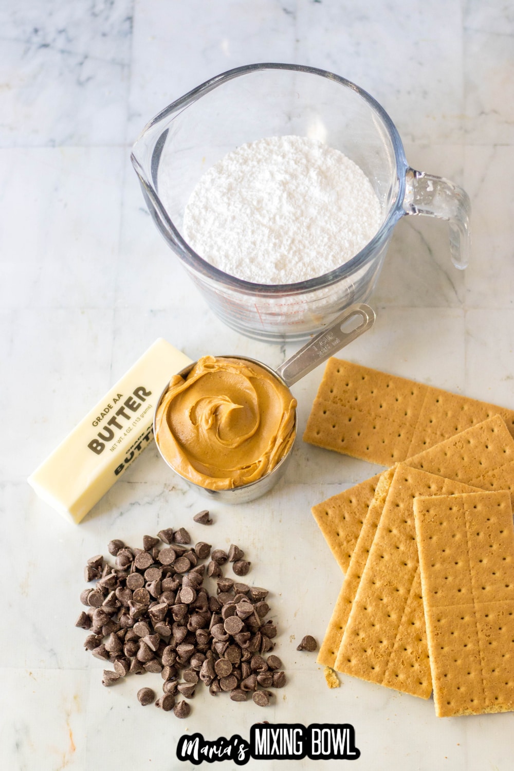 powdered sugar, peanut butter, butter, chocolate chips, and graham crackers on a marble backdrop