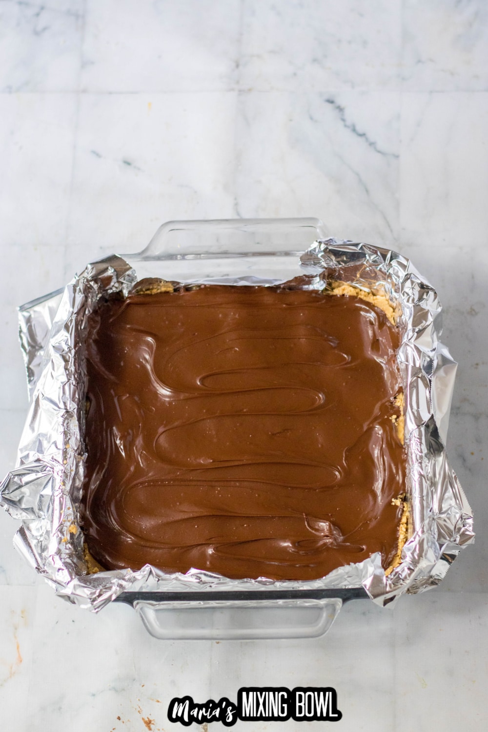 chocolate being spread on bars in a glass baking dish