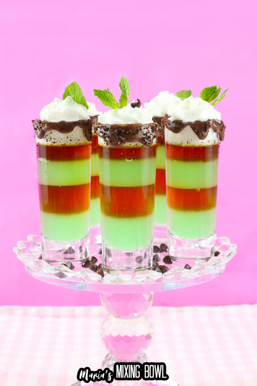 four mint shots on a clear glass cake stand
