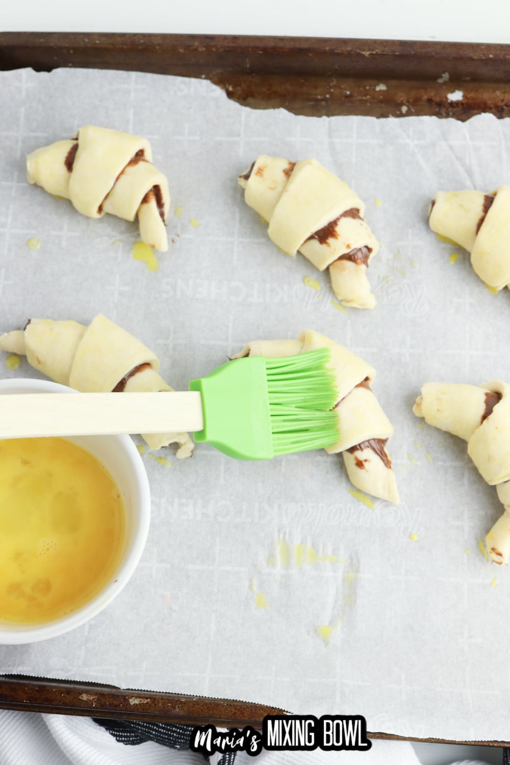 crescent rolls filled with nutella and chocolate being brushes with melted butte r