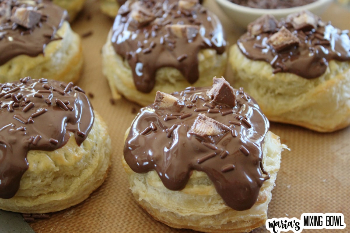 donuts being frosted with melted chocolate and reese's cup