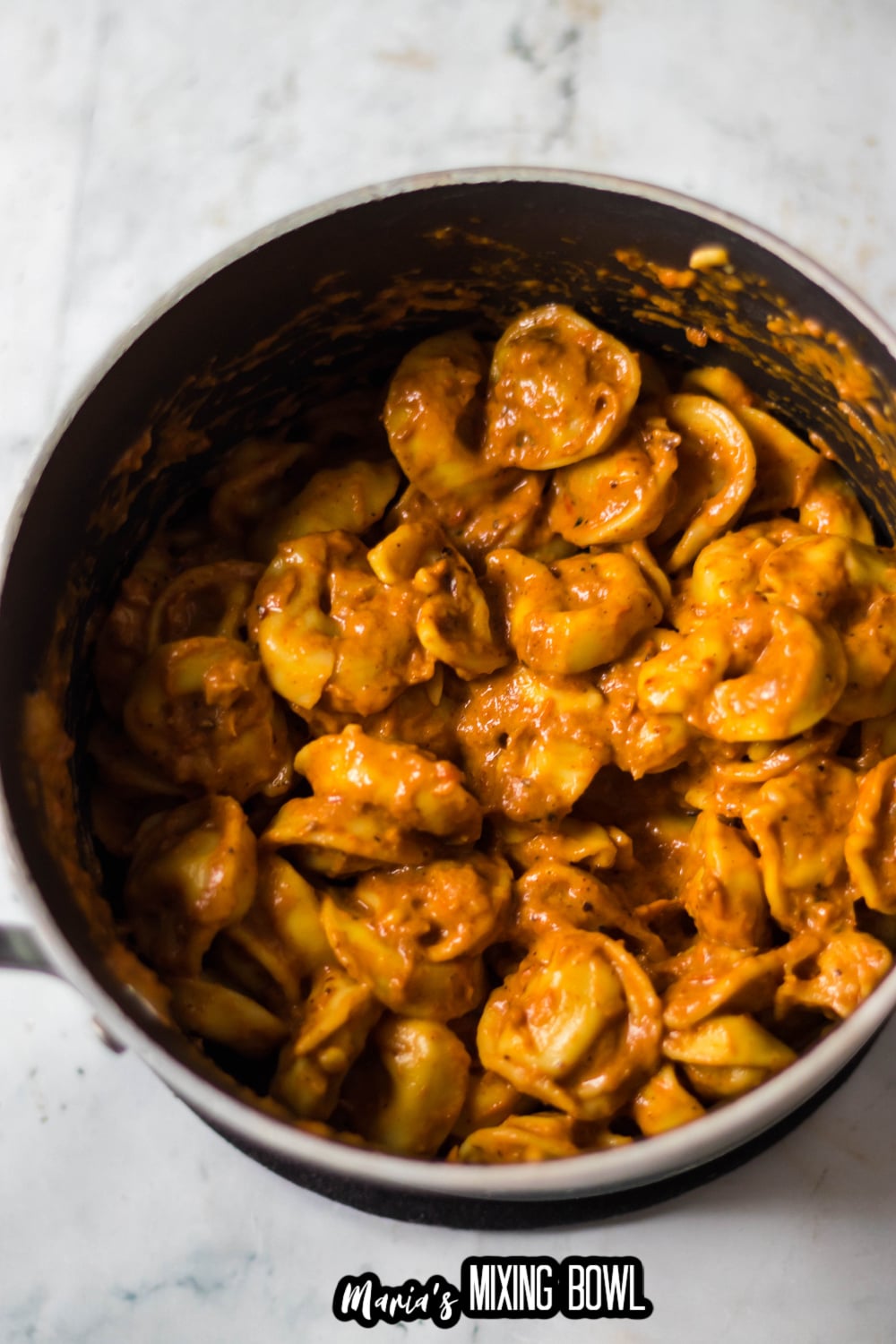 tortellini being coated in sauce
