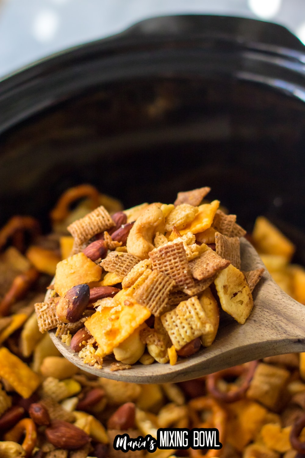 large wooden spoon with a scoop of chex mix held in the air