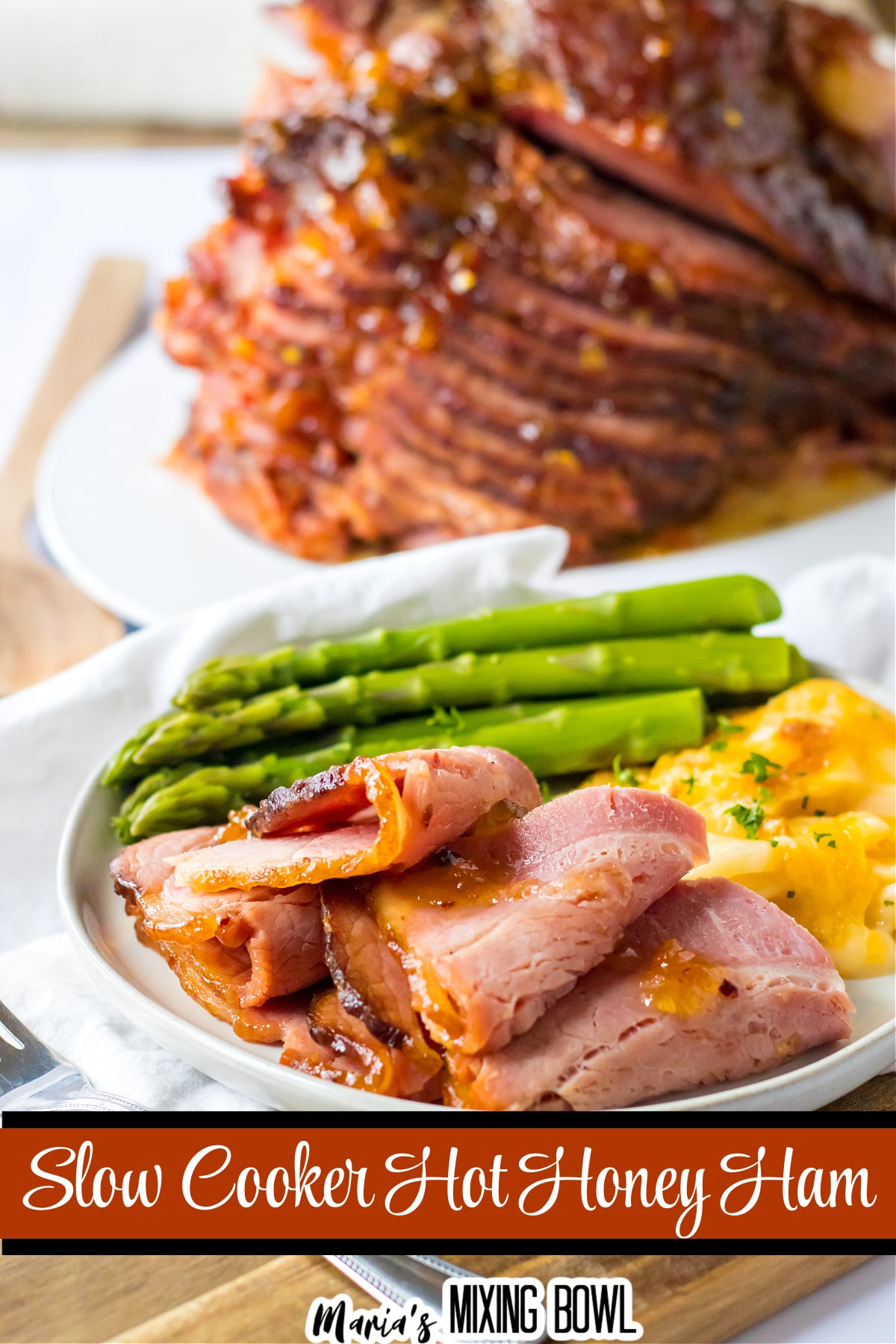 close up of slices of hot honey ham on a white plate with asparagus and au gratin potatoes