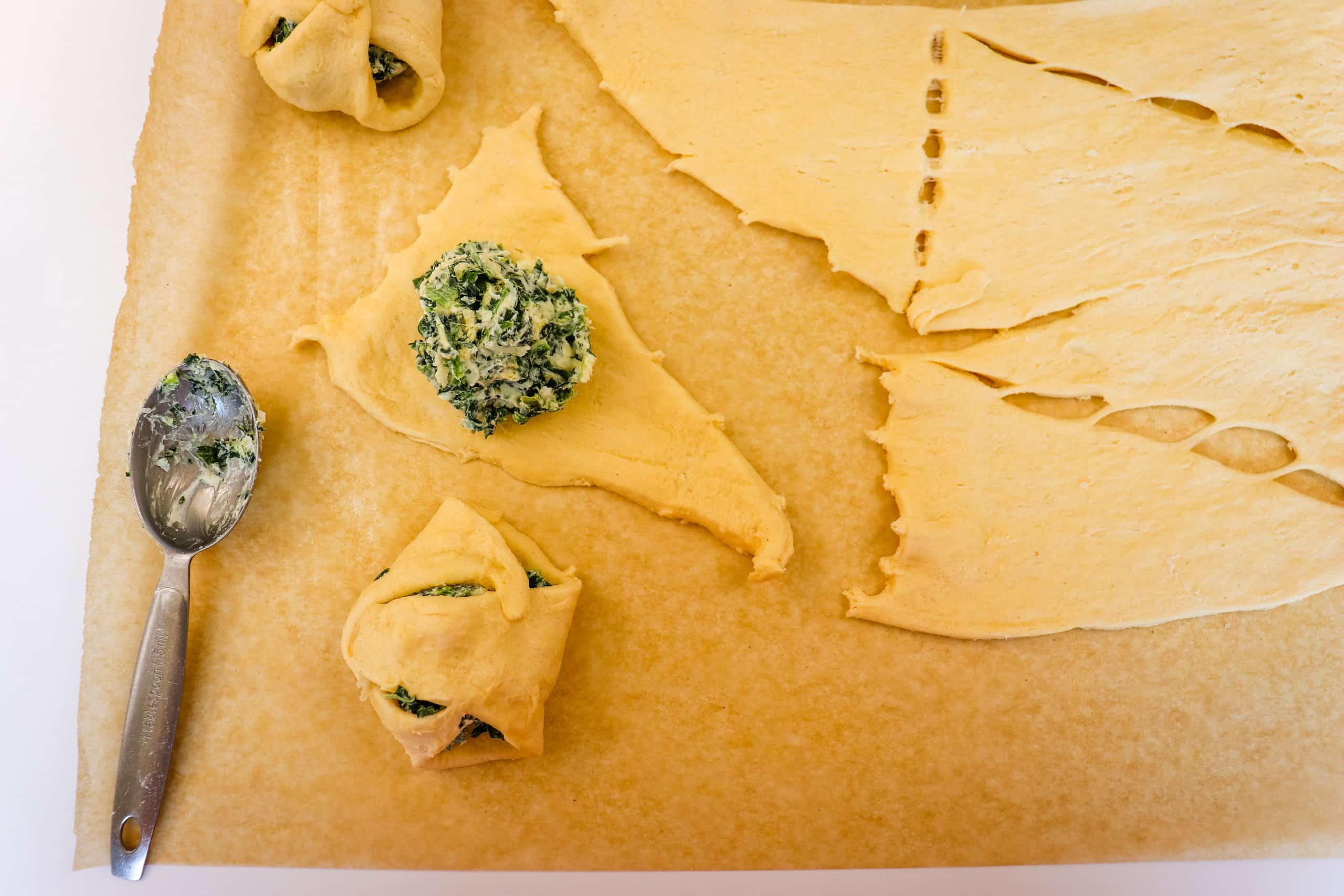spinach and cheese mixture being rolled into crescent rolls