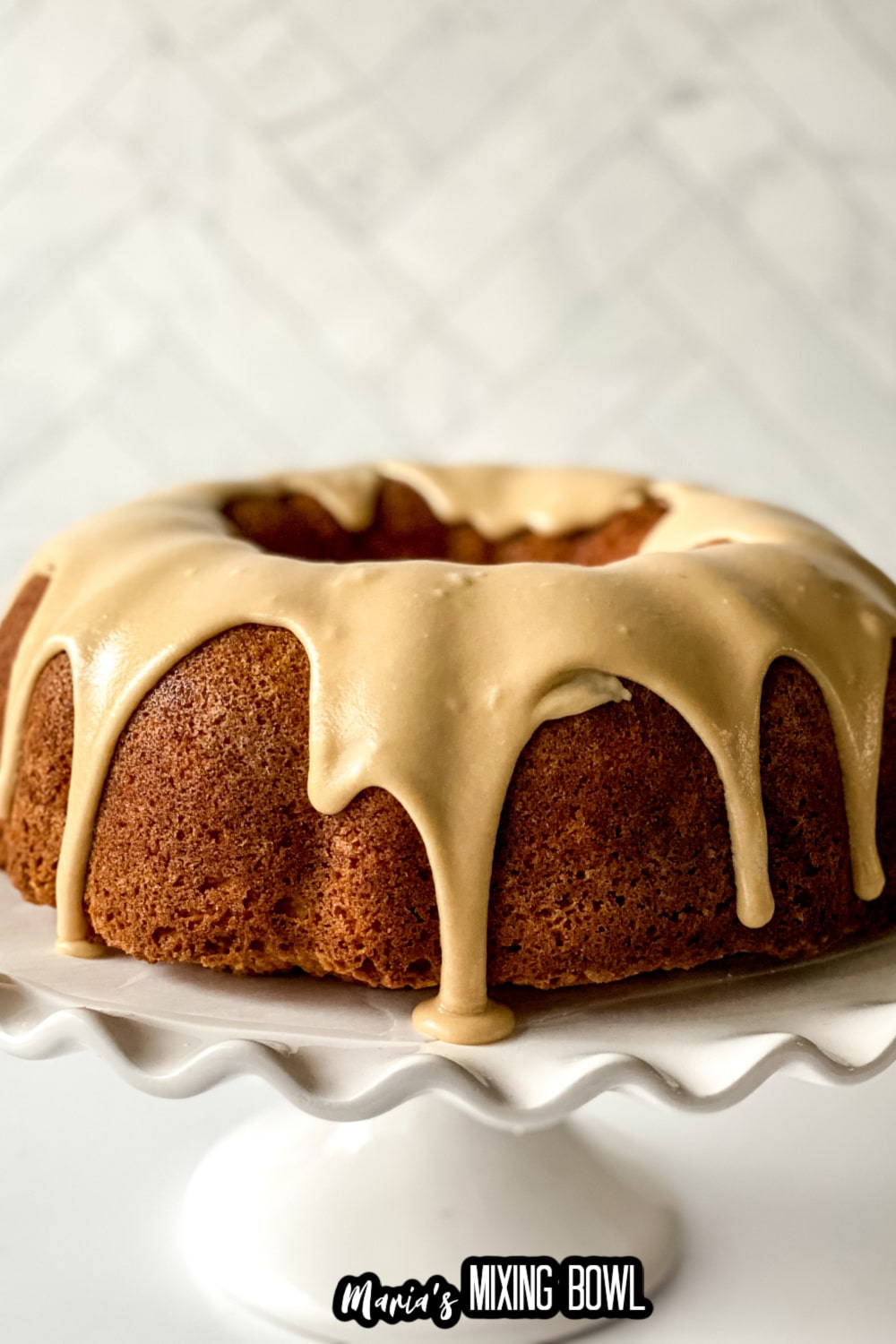 uncut vanilla buttermilk pound cake on a white cake stand