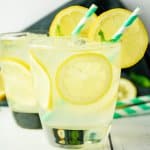 two cocktail glasses filled with lemon cocktail with a green and white straw