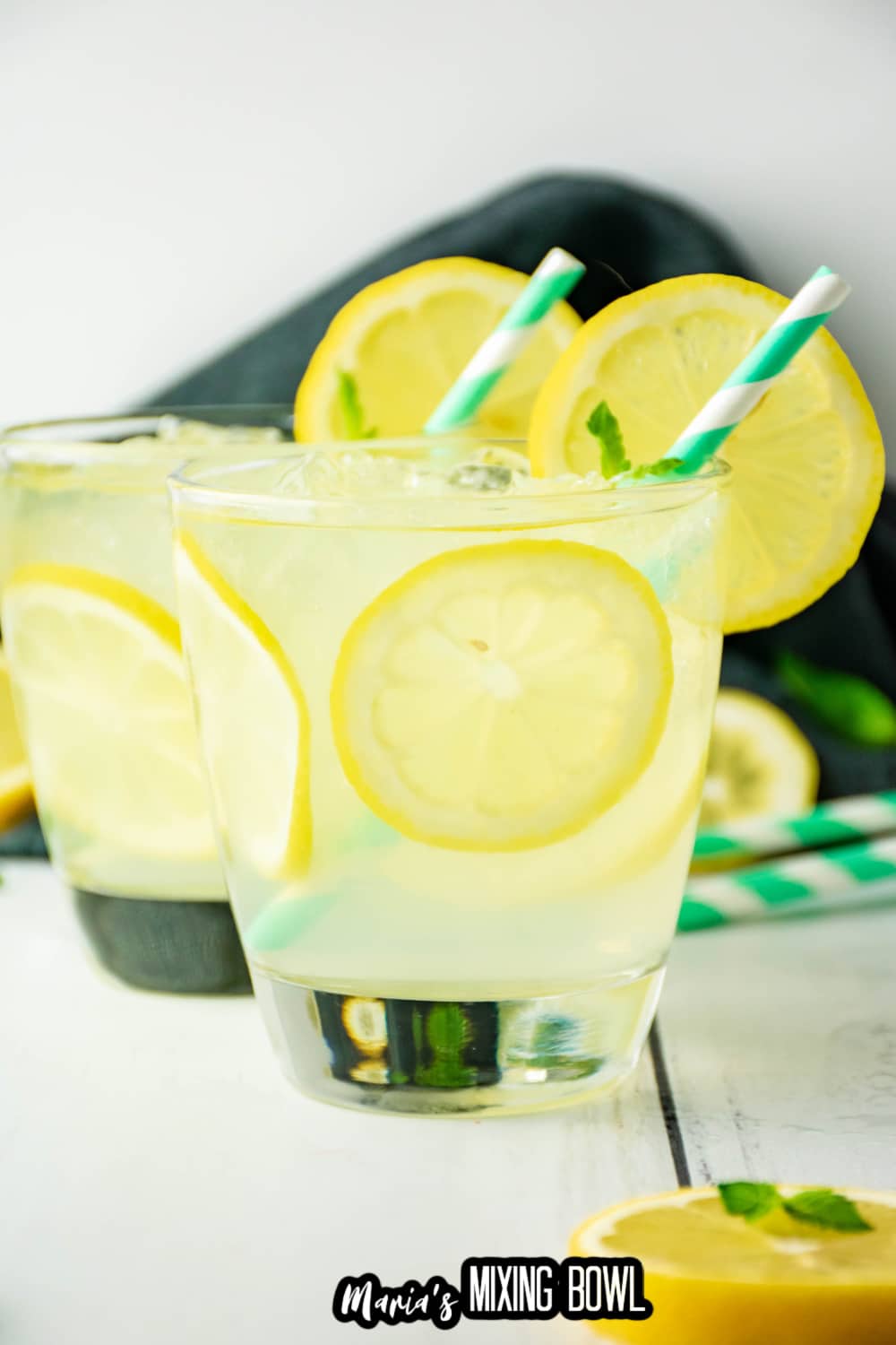 two cocktail glasses filled with lemon cocktail with a green and white straw