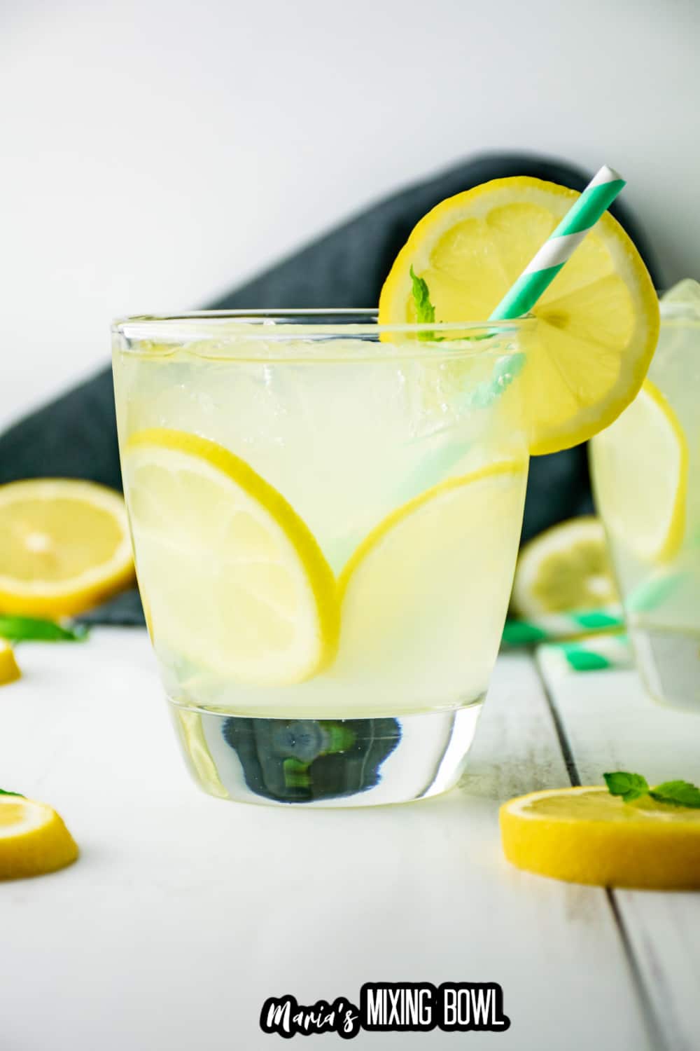 cocktail glass filled with lemonade cocktail with a green and white straw