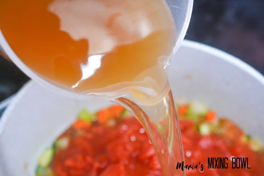 broth being poured into vegetables in a large pot